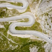 Aerial view of a winding road in a mountainous landscape with two cars.