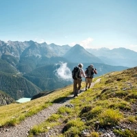 Two hikers on a mountain trail overlooking a mountain landscape.