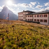 Hotel in alpine setting with Matterhorn in the background at sunset.