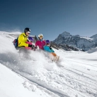 A family on a sled is riding down the snowy mountain.