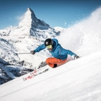 A skier turning on a snowy slope with a mountain in the background.