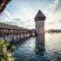 An old wooden bridge with a tower in the water at sunset.
