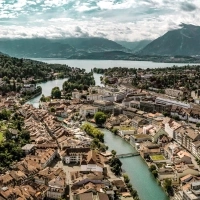 City view of Thun in Switzerland with a castle, river, and mountains in the background.