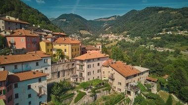 Maisons colorées sur un versant vert sous un ciel bleu.