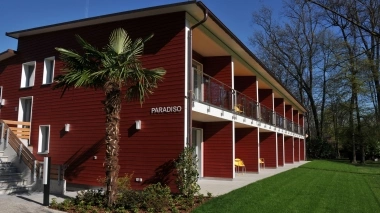 Zweistöckiges rotes Gebäude mit Palmen und dem Schriftzug "Paradiso".