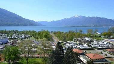 Une vue large sur un lac avec des montagnes environnantes et un camping au premier plan.