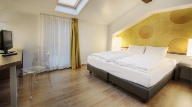 A modern, bright bedroom with a double bed, skylight, and stylish decor.