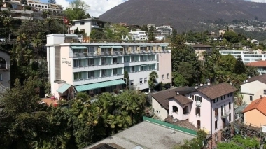 Hotelgebäude in einer bergigen, grünen Umgebung.