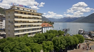 Hotel building by the lakeside with mountains in the background.