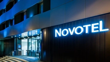 An illuminated Novotel hotel entrance at night with modern glass and metal structures.