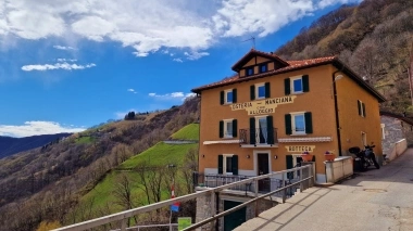 Auberge jaune à la montagne sous un ciel bleu.