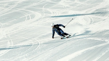 A skier in a turn on a freshly groomed slope.