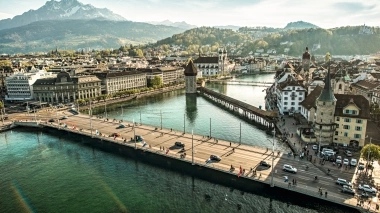 Aerial view of a historic bridge and old town with mountains in the background.