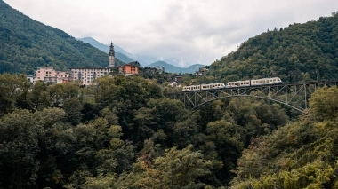 A mountain city with a train crossing a bridge.