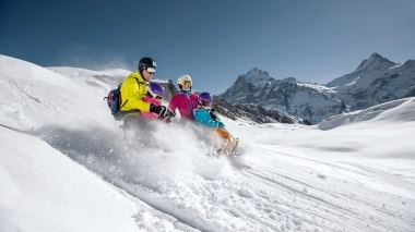 Una famiglia su una slitta sta scendendo giù per la montagna innevata.