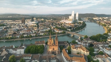 Luftaufnahme einer Stadt am Fluss mit Brücken und modernen Gebäuden im Hintergrund.