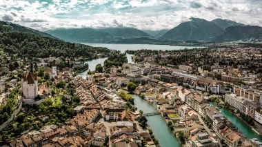 Stadtansicht von Thun in der Schweiz mit Burg, Fluss und Bergen im Hintergrund.