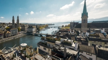 View of Zurich with church, river, and bridge in sunny weather.