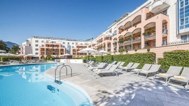 Extérieur d'un hôtel avec piscine, transats et parasols.