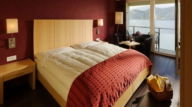 Cozy hotel room with double bed, red walls, and lake view.