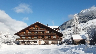 Eine verschneite Hütte in den Bergen bei klarem Himmel.