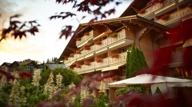 Exterior view of the chalet-style Hotel Gstaaderhof with flowers in the foreground