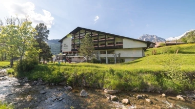 A stream, green meadows and a playground in front of a hotel