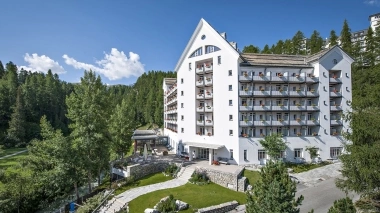 Hotel building surrounded by trees under a clear sky in summer