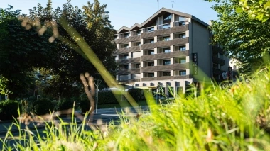 Hotel des Alpes in Flims, umgeben von Grün, an einem sonnigen Tag.
