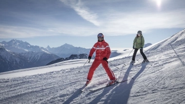 Two skiers on the slopes with mountains in the background