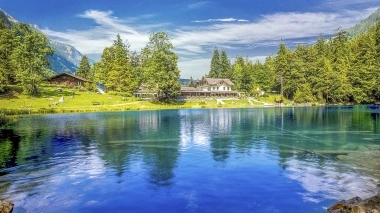 Aussenansicht vom Hotel mit Blausee im Vordergrund, umgeben von Bäumen
