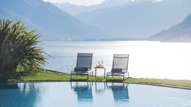 Two deck chairs by the pool with the lake and mountains in the background