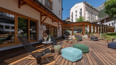 Terrasse ensoleillée de l'hôtel Schweizerhof Lenzerheide avec fauteuils à bascule