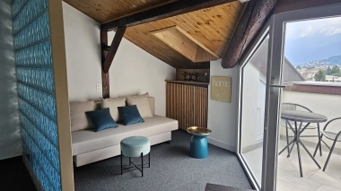 Canapé sous un toit en pente, avec un balcon sur la droite.