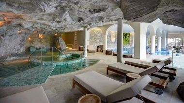 Wellnesspool und Liegestühle in einem höhlenartigen Innenraum.
