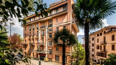 Ein durch Palmen verstecktes mehrstöckiges Hotelgebäude.