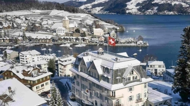 Foto aerea invernale dell'hotel con lago e montagne sullo sfondo.