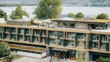 Moderno edificio alberghiero situato in riva al lago e circondato da alberi.