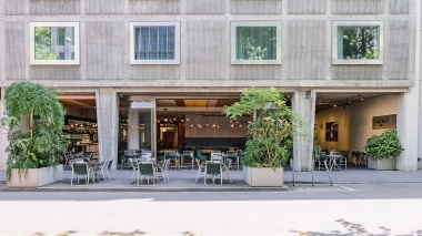 Moderno edificio alberghiero con ristorante aperto e tavoli all'aperto.