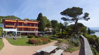 Exterior view of the hotel with well-kept gardens in sunny weather.