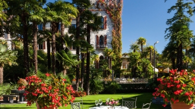 Well-kept hotel gardens lined with palm trees in sunny weather.