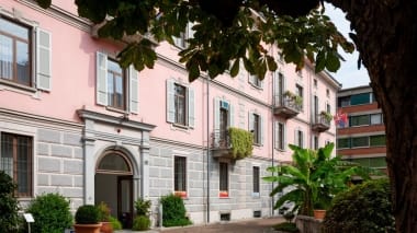 Casa con la facciata rosa dietro un albero.