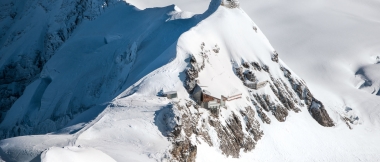 Une station de montagne enneigée au sommet avec une couverture de neige environnante.