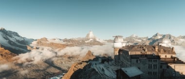 Un osservatorio nelle Alpi con vista sul Cervino e il paesaggio montano circostante sotto un cielo limpido.
