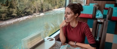 A person sitting in a train, passing a river