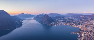 Vista su una città in riva al lago, circondata dalle montagne nell’atmosfera serale.