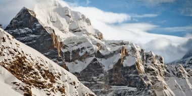 A snowy mountain landscape under a blue sky.