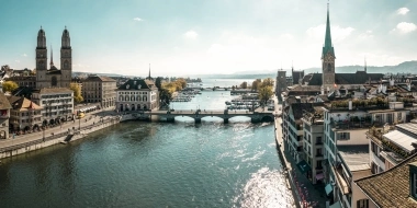 Aerial view of a historic town with river, bridge, and church steeples.