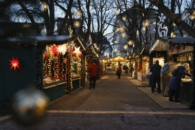 Eine festlich beleuchtete Weihnachtsmarktgasse mit geschmückten Ständen und Besuchern.