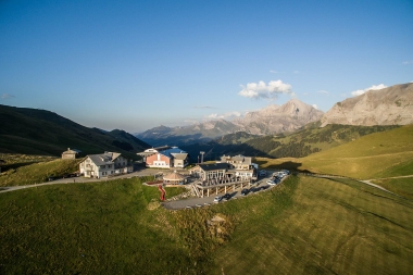 A mountain station with buildings, parking lot, and mountains in the background under a clear sky.